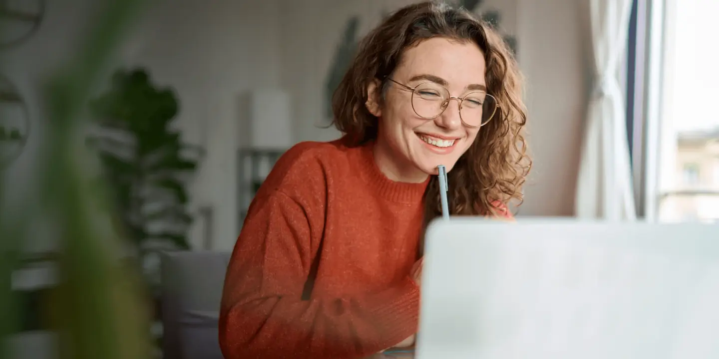 Persona estudiando frente a una computadora portátil, tomando notas